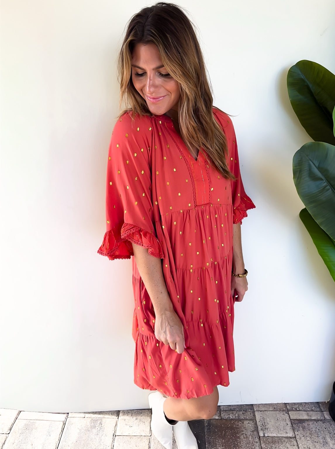 Angled view of the terracotta Copper Confetti Dress with gold metallic dots and white boots.