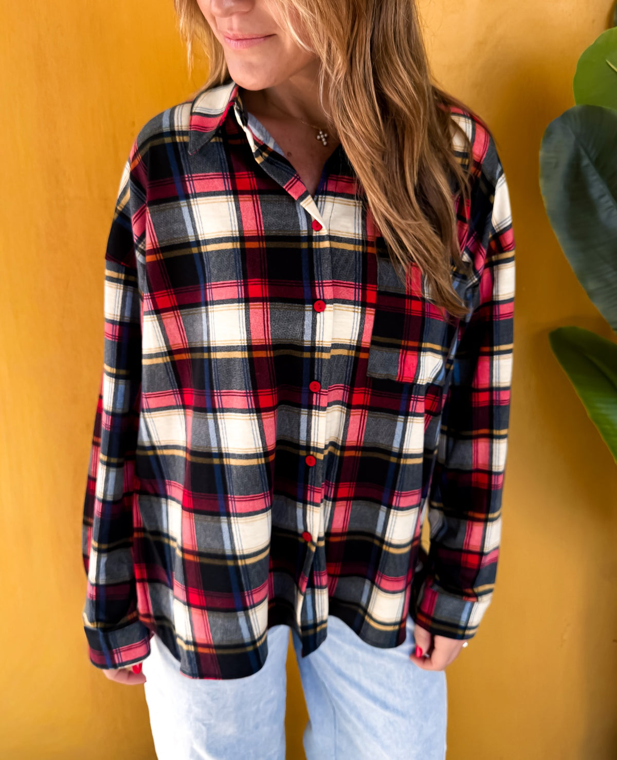 Close-up of the plaid pattern, red buttons, collar, and chest pocket.